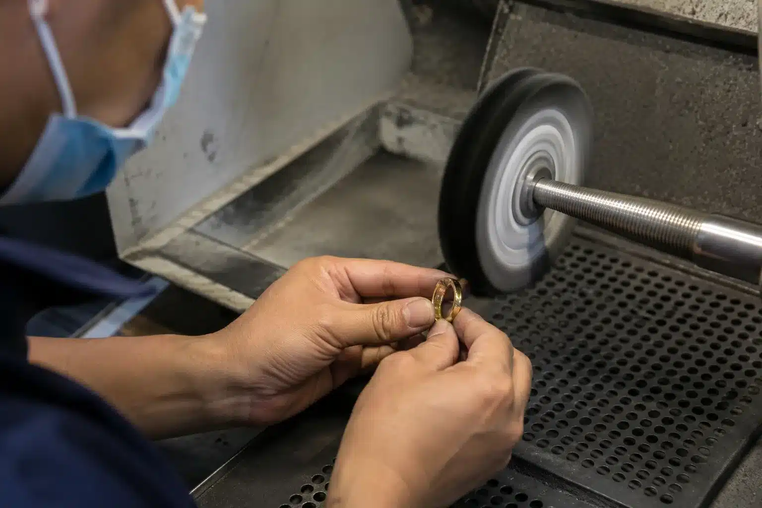 Jewelry worker polishing a stainless steel ring during surface preparation before PVD coating, creating a mirror-like finish for long-lasting jewelry plating.